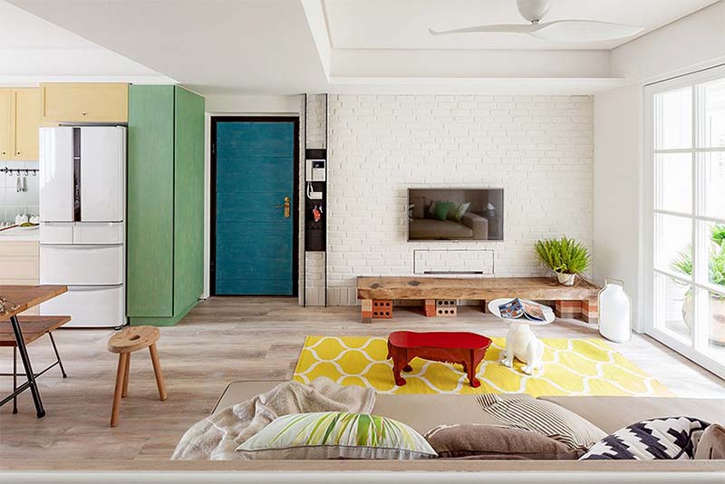 Chủ nhà trang trí phòng khách bằng rất nhiều gam màu tự nhiên và rực rỡ như xanh lá cây, trắng, vàng, đỏ, nâu gỗ tường gạch mộc